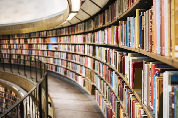 Curved wooden bookshelf filled with colorful books along a circular library wall.